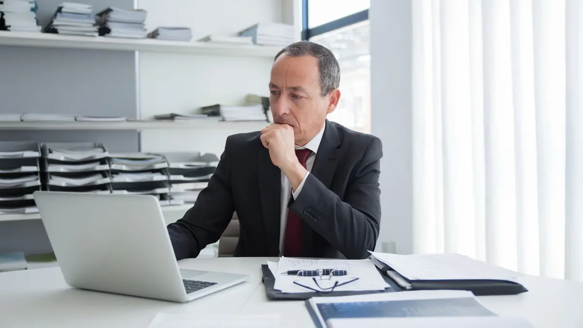 Homme d’affaires pensif devant son ordinateur portable, à son bureau